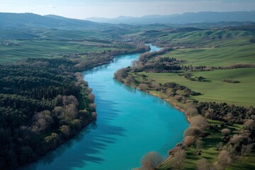 Serene aerial view reveals a winding turquoise river through rolling green hills and valleys on a