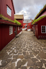 Historic cobblestone courtyard with red turf-roofed wooden houses