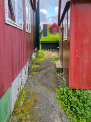 Narrow passage between colorful wooden houses with grass roofs