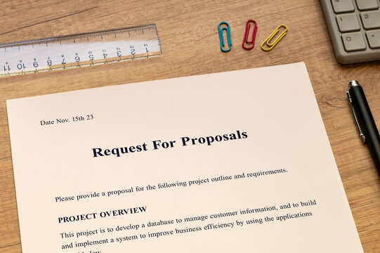 The binder containing the Request For Proposals documents is on the desk, along with a calculator and pencil.