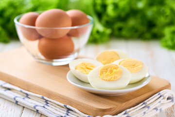 Sliced boiled chicken eggs on a light kitchen table, selective focus.