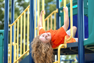 Happy child playing outside. Smiling kid on playground bars. Cheerful boy having fun. Playful child outdoors in park. Fun childhood summer activity. Laughing kid climbing on playground.