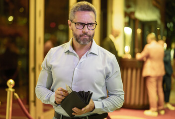 Rich business man holding wallet with money. Rich businessman counting dollars bills money. Wealthy rich man with a wallet and money cash. Businessman in urban nightlife hold wallet. Rich lifestyle.