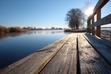 Wooden pier extends over still, deep blue water, reflecting the serene morning sunlight and bare