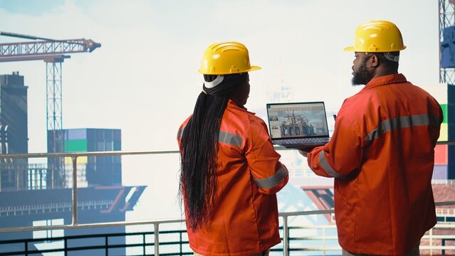 Offshore platform employees use performance management software to observe operations. Crew uses laptop program integrating sensor readings to manage industrial barge operations,