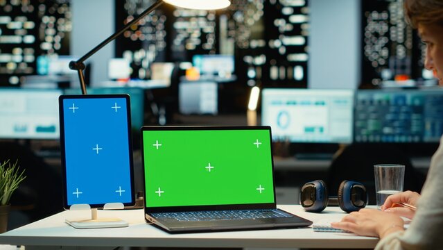 Executive manager at desk uses green screen on laptop and blue screen on tablet, scheduling new meetings and planning the weekly agenda. Business management tasks for a project. Camera B. - Powered by Adobe