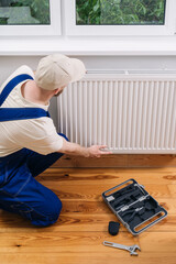 Home heating maintenance with a technician working on a radiator