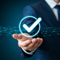 Businessman in suit holding glowing holographic checkmark over digital grid network symbolising success validation and approval