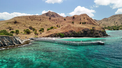 Scenic overhead aerial landscape of Komodo Island’s Pink Beach surrounded by lush green hills