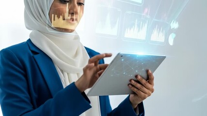 A woman in a headscarf, looking at data projected in front of her, using a tablet - Powered by Adobe