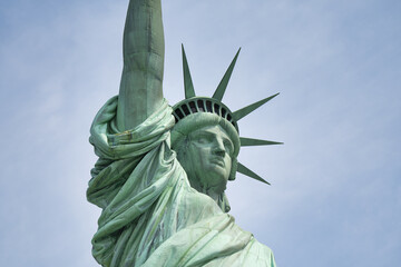 Fototapeta premium Close-up frontal perspective of Liberty Enlightening the World monument with harbor background