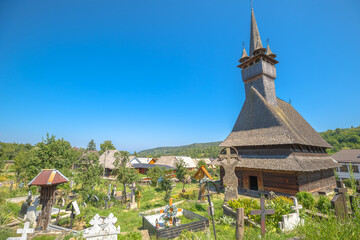 Saint Nicholas wooden church with its tall spire standing proudly on a sunny day, showcasing traditional Maramures architectural heritage in rural Romania. Maramures of 1600s