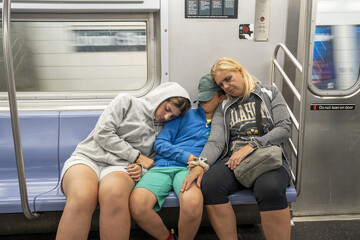 Exhausted mother with two children sleeping on subway train in New York City