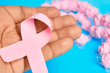 Hand holding a pink ribbon conveying personal support empathy caregiving and advocacy for breast cancer prevention and awareness
