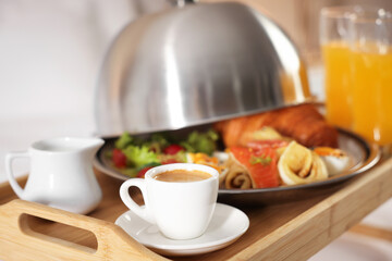 Tray with delicious breakfast on bed in hotel room, closeup