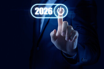 Businessman activating 2026 year by pressing power symbol on virtual screen against dark blue background, closeup. Ready for new year