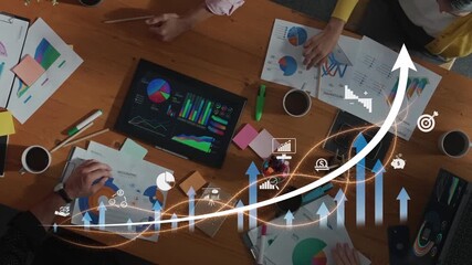 A dynamic business meeting featuring a diverse team analyzing charts and strategies over a wooden table, showcasing teamwork and digital planning processes. Raster - Powered by Adobe
