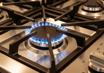 Close-up of modern gas stove burner with blue flame. Stainless steel cooktop in contemporary kitchen. Home appliance for cooking and heating.