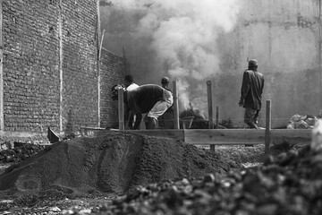 Black and white photo of workers doing construction work with smoke in the background