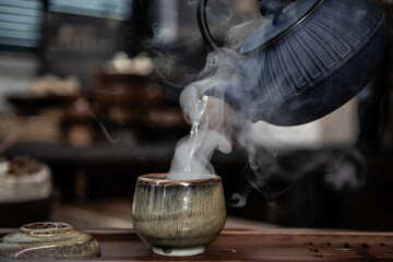 Hand Pouring Hot Water into a Steaming Tea Cup