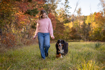 Young Woman Walking with Dog in a field in the Fall
