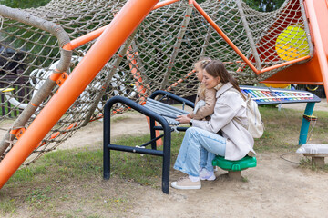 Fototapeta premium Young woman and little girl playing xylophone at an outdoor playground
