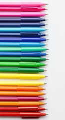 Fototapeta premium Multiple writing instruments display a spectrum of vibrant colors arranged vertically on a plain background