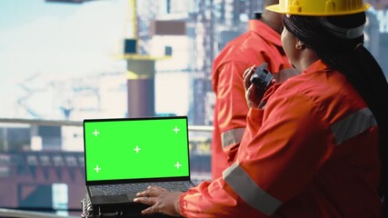 Isolated screen laptop used by energy production company worker to determine optimal drilling rig locations. Woman on offshore platform ship looking at well sites data on mockup notebook, camera B