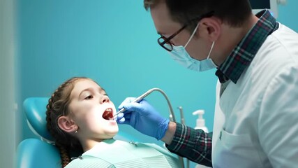 Dentist Examining Girl's Teeth with Blue Gloves and Medical Mask in a Blue Room