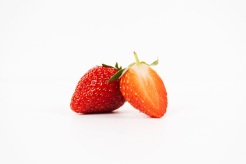 Whole strawberry and half slice lean together showing red exterior and juicy inner flesh isolated on white.