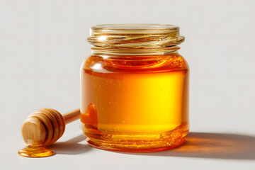Glass Jar Filled with Golden Amber Honey and Wooden Dipper on a Light Background