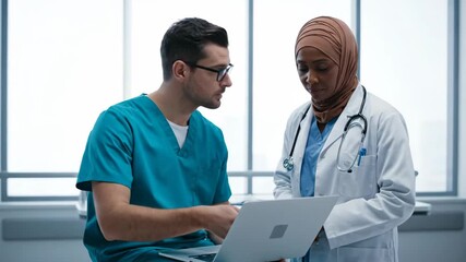 Focused Medical Professionals Examining Data on Laptop in Bright White Room - Powered by Adobe
