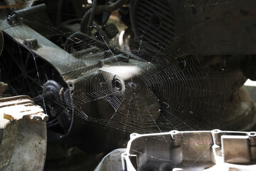 Large spiderweb on an abandoned old engine. dirty mechanical machine part has an industrial grunge...