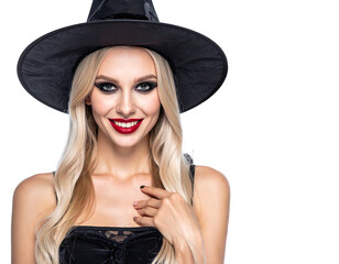 Smiling blonde woman in witch hat and black outfit against a black backdrop, looking directly at the viewer