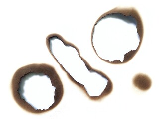 Close up of burned hole on white paper background. Black burn mark and scorched paper texture. A...