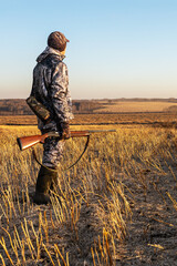 man hunter with gun while walking on field. hunting season.