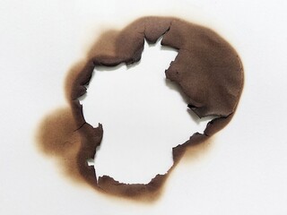 Close up of burned hole on white paper background. White paper with fire burned hole. Fire damage with paper burn mark and charred edge texture.