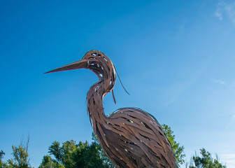 Metal heron sculpture against a blue sky