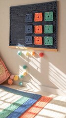 Cheerful playroom corner with handmade crochet wall hanging. This colorful yarn grid decoration creates cozy and playful atmosphere for kids