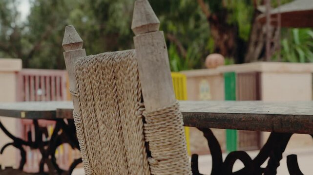 Close-up of a handmade chair with a woven seat in a Moroccan courtyard. The rustic furniture adds to the tranquil ambiance of this North African setting.