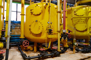 Yellow industrial tanks in a processing facility showcasing machinery and pipes during daytime operations