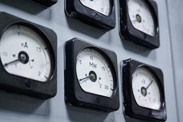 Detailed view of electrical gauges on a control panel in a power plant during daytime operations