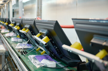 Televisions moving along conveyor belt in industrial manufacturing plant during production process