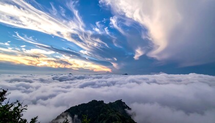 Mountain peak emerges from sea of clouds, vast sky filled with swirling clouds