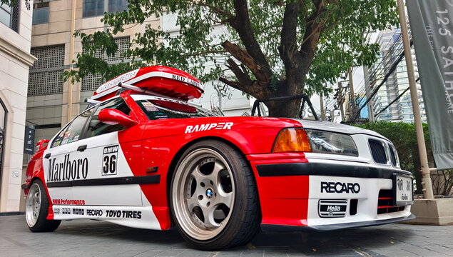 Modified BMW E36 with Marlboro racing livery, sponsor decals, and M3-style trim parked in an urban setting in the Thai capital