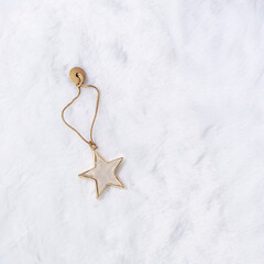 Christmas bauble shiny golden star in beige gold tones, flat lay on white fur. Festive holiday...
