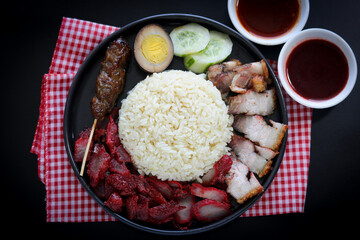 Top view of Hainanese-style mixed rice (Nasi Campur Hainam) featuring assorted porks, soy-braised egg, cucumber and satay.