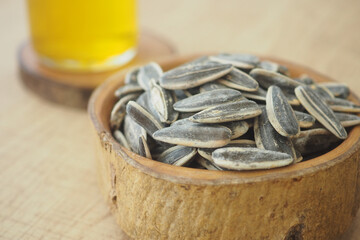 Sunflower seeds in wooden bowl with drink nearby