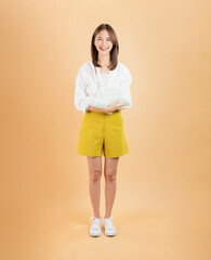 Asian woman broken arm wrapped and stand on isolated on beige color background.