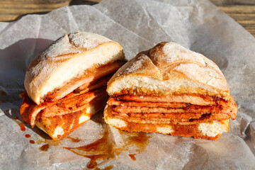 A thick Peameal Bacon sandwich, sliced open to show the many layers of cured pork and sauce.